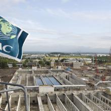 Aerial overview of NAC flag suspended in front of tanks being constructed