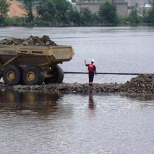 Backfilling rocks across water to create dam