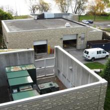 Building with two overhead doors behind gated transformers and enclosure