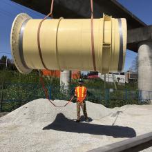 NAC individual supervising large process pipe being lifted by crane