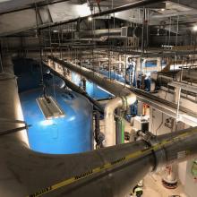 Ceiling view of suspended process pipes leading into enclosed tanks