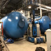 Genie lift next to two large boilers